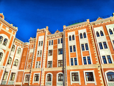 An ornate brick building with distinctive architecture stands tall against a vibrant blue sky, showing its intricate design.の写真素材