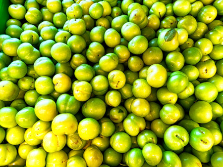 An abundance of fresh green plums fills the market display, highlighting their vibrant color and inviting textures.の写真素材