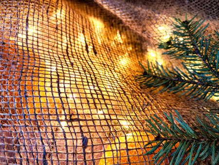 Background with bouquet and branches of spruce, bright glowing garlands and burlap. Abstract texture and frame for Christmas and New Year. Place for text and copy spaceの写真素材