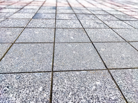A close-up view of a gray stone pavement showing casing textured patterns in bright natural light,...