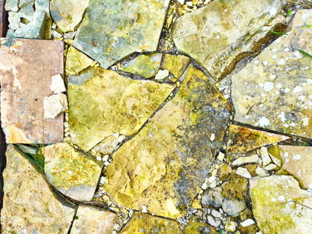 A mosaic of differently shaped stones is laid out in a path, showing unique textures and vibrant...