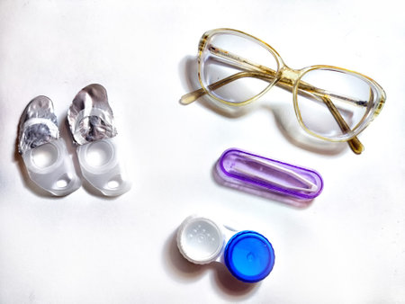 A pair of stylish glasses is placed alongside contact lens case and solution, showcasing daily eyewear essentials for eye careの写真素材