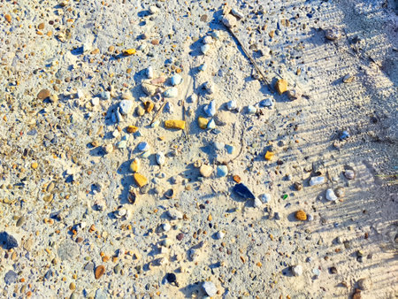 Pebbles create a design on a sandy beach under a clear blue sky.の写真素材
