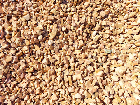 Small, colorful gravel stones cover the ground at a construction location under clear blue skies.