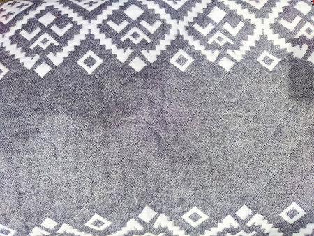A close-up view of textured fabric displaying intricate geometric patterns in shades of gray, ideal...