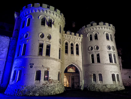 A view of Sheremetyevo Castle, illuminated at night in Russia. The castle's stone walls and towers are lit in soft blue lightの写真素材