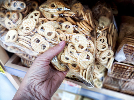 A person selects a bag of delicious cookies while shopping at a local store. Difficult balancing treats with a healthy lifestyle choiceの写真素材