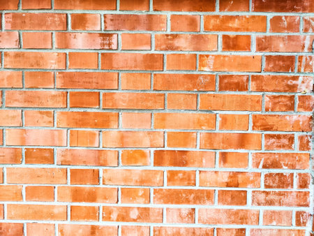 A uniform red brick wall showcases the texture and arrangement of bricks.の写真素材