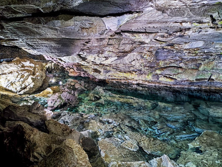 A view from the edge of a clear blue water pool inside large, underground cave