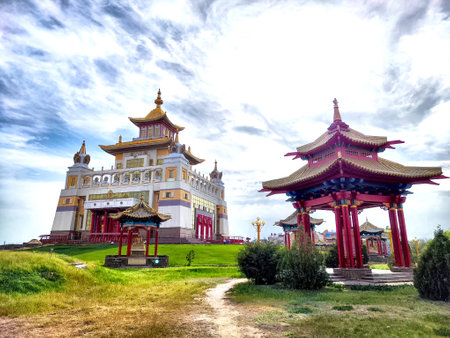 Visitors admire the impressive Golden Buddha Temple in Elista, surrounded by peaceful gardens and traditional structures under a bright sky.の写真素材