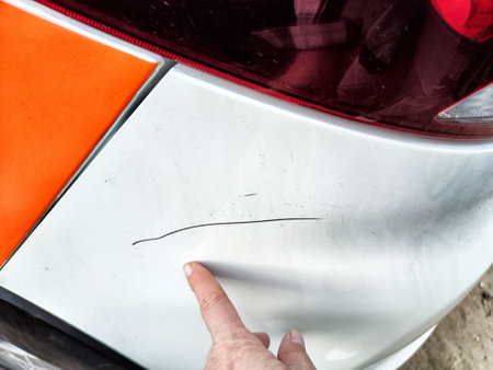 A person points at visible scratches on a damaged car's rear, highlighting the impact from the recent accident.の写真素材