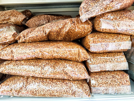 Red lentils are packaged in clear plastic bags and arranged on shelves in a grocery store aisle,...