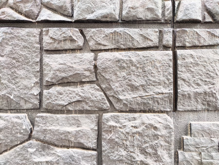 Gray stone wall displays a detailed texture with various patterns and ample areas for adding text or decorative elements.の写真素材