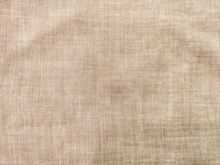 Beige fabric displays a soft texture with subtle patterns, providing a versatile background for various creative projects.の写真素材