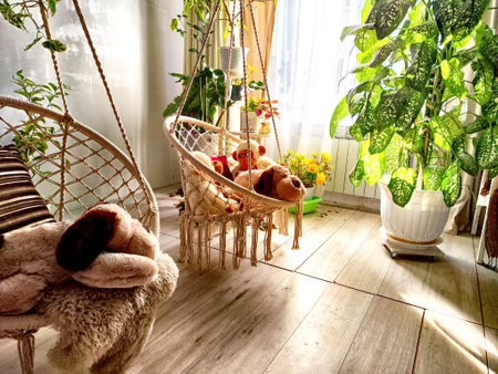 Modern cozy beautiful room with a braided rope macrame chair, green plants and a window with...