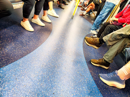 Hong Kong, China - April 09, 2024: A group of diverse people on the subway engaged in conversation and checking their devices during a busy afternoon.の写真素材