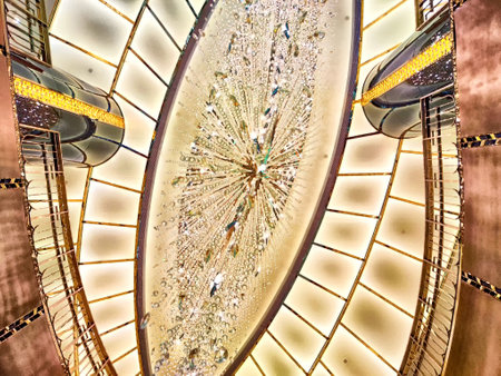 A captivating chandelier shines brilliantly beneath an expansive ceiling, enhancing the...
