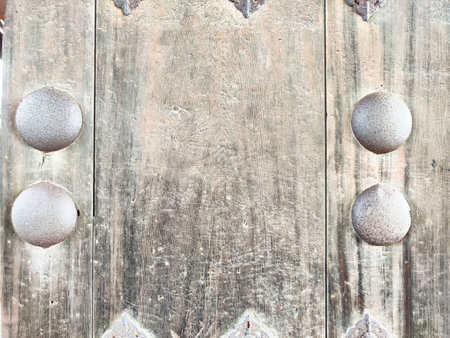 Rustic wooden surface features round metallic details, providing a textured backdrop suitable for...