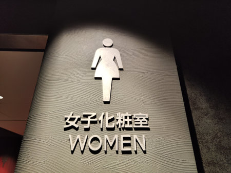 Bilingual sign indicating women's restroom with a simple design and textured wall background for clear identification.の写真素材