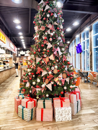 A beautifully decorated Christmas tree stands in a cafe, adorned with ornaments and surrounded by colorful wrapped presents.の写真素材