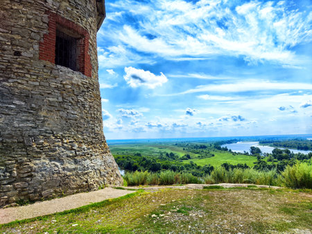 A stunning view from a historic stone tower reveals a vast landscape with a river and rolling hills...