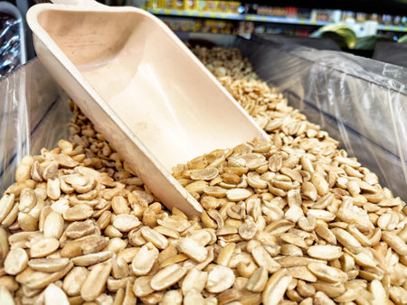 Bins filled with a variety of nuts are showcased in a store, with a scoop placed on the mounds....