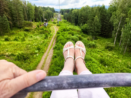 Enjoying a thrilling cable car journey through serene mountain terrain surrounded by vibrant greenery and towering trees.の写真素材