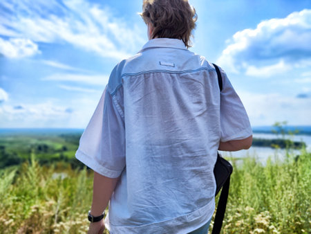 Individual stands at a scenic overlook, taking in the expansive view of the hills and river below on...