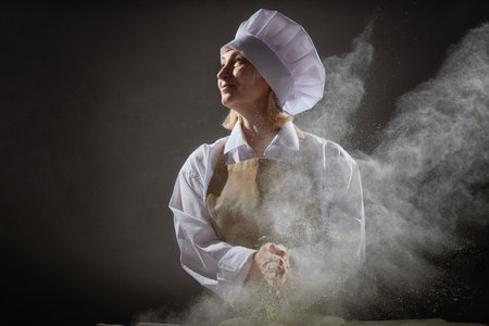 An elderly woman playfully cooking with flour during a humorous kitchen photo shootの写真素材
