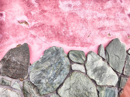 A vibrant pink wall texture displays a mix of smooth and rough stones, suitable for adding personalized text or graphics.の写真素材