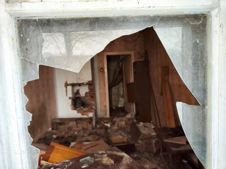 Interior of an old house with a broken window in the foreground