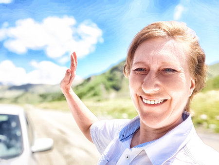 A woman wearing a crisp white shirt is joyfully smiling in front of an impressive mountain backdrop, radiating happiness and warmthの写真素材