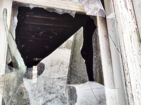 Shattered glass fragments surround an empty space indicating neglect in an abandoned building. Light...