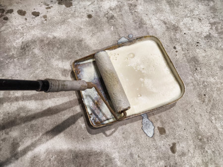 A worker applies primer using a roller on the floor to prepare it for laying tiles in a room undergoing renovation.の写真素材