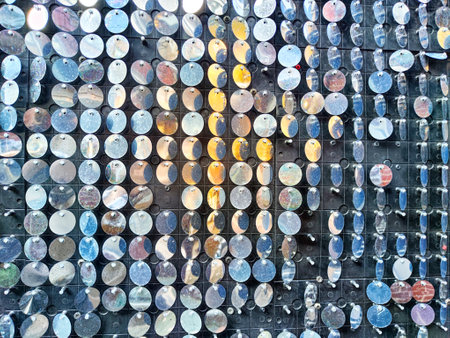 An artistic surface showcases shiny circular pieces arranged in a structured manner, creating a...