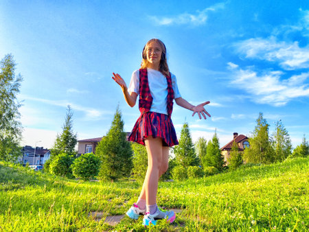Young girl enjoys playful moment in nature on a sunny day with blue skies and vibrant green grassの写真素材