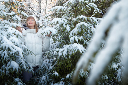Woman enjoying a winter walk in a snow-covered forest during the Christmas and New Year seasonの写真素材