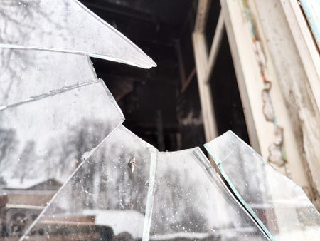 Broken window glass shows a cloudy view of the interior space, hinting at neglect with reflections...