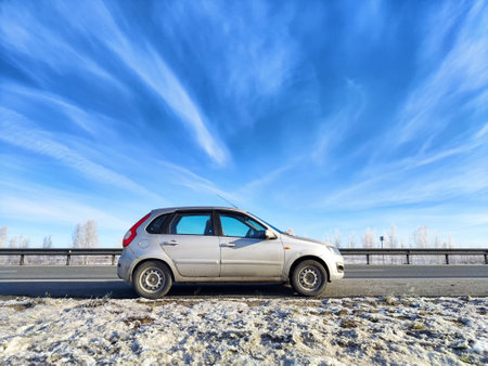Car navigating an icy road in winter, showing the challenges of travel in cold weather amid a scenic, snowy area.の写真素材