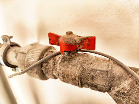 Old, dusty pipes with a red valve suggest long-term disuse, reflecting neglect in this forgotten structure's maintenance.の写真素材