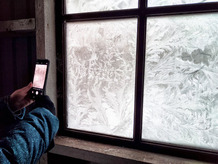 Frosted glass displays stunning snow patterns as someone takes a picture, showing the beauty of...