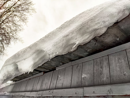 Thick snow covers the roof, posing a risk of collapse as it melts under the cold winter conditions.