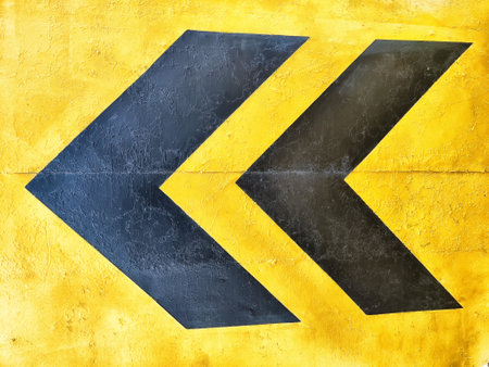 Black arrows on a yellow background signal a left turn, emphasizing the intersection of direction and design in urban spaces.の写真素材