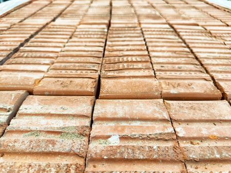 Close-up view of terracotta tiles aligned perfectly on a rooftop, highlighting their rustic texture under bright daylight.の写真素材