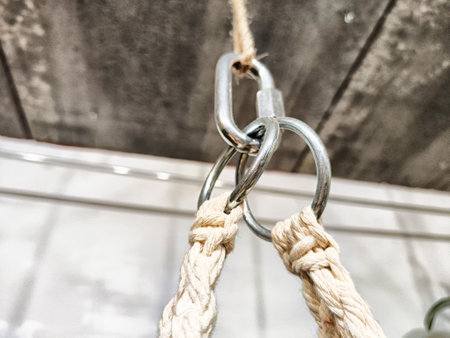 Metal carabiners connected to braided rope in a minimalist indoor space with a rustic ambiance.の写真素材