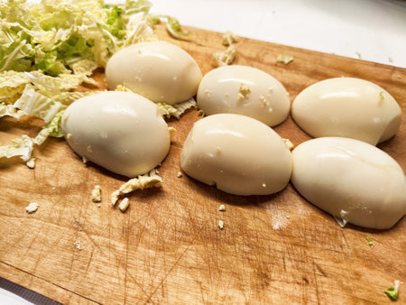 Soft boiled eggs sit next to freshly chopped cabbage on a wooden cutting surface in a cozy kitchen...