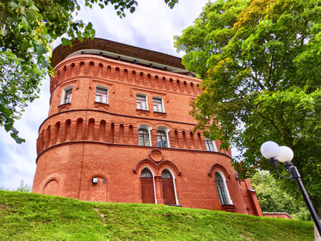 Red brick structure with ornate detailing stands in lush park, under cloudy sky, inviting exploration and curiosity.の写真素材