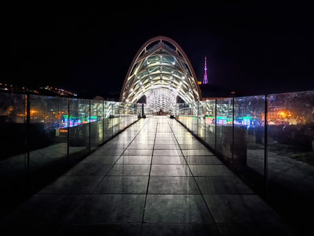 A contemporary pedestrian bridge stands illuminated at night in Tbilisi, showcasing vibrant city lights.の写真素材