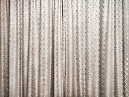 Delicate curtain fabric featuring a subtle diamond pattern creates a warm atmosphere in a modern indoor space, perfect for homes.の写真素材