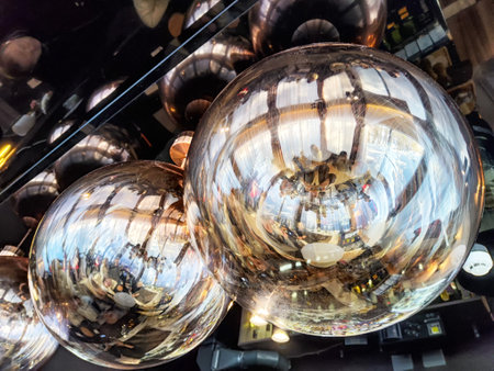 Unique light fixtures reflect the vibrant atmosphere of a busy cafe with patrons enjoying their time during daylight hours.の写真素材